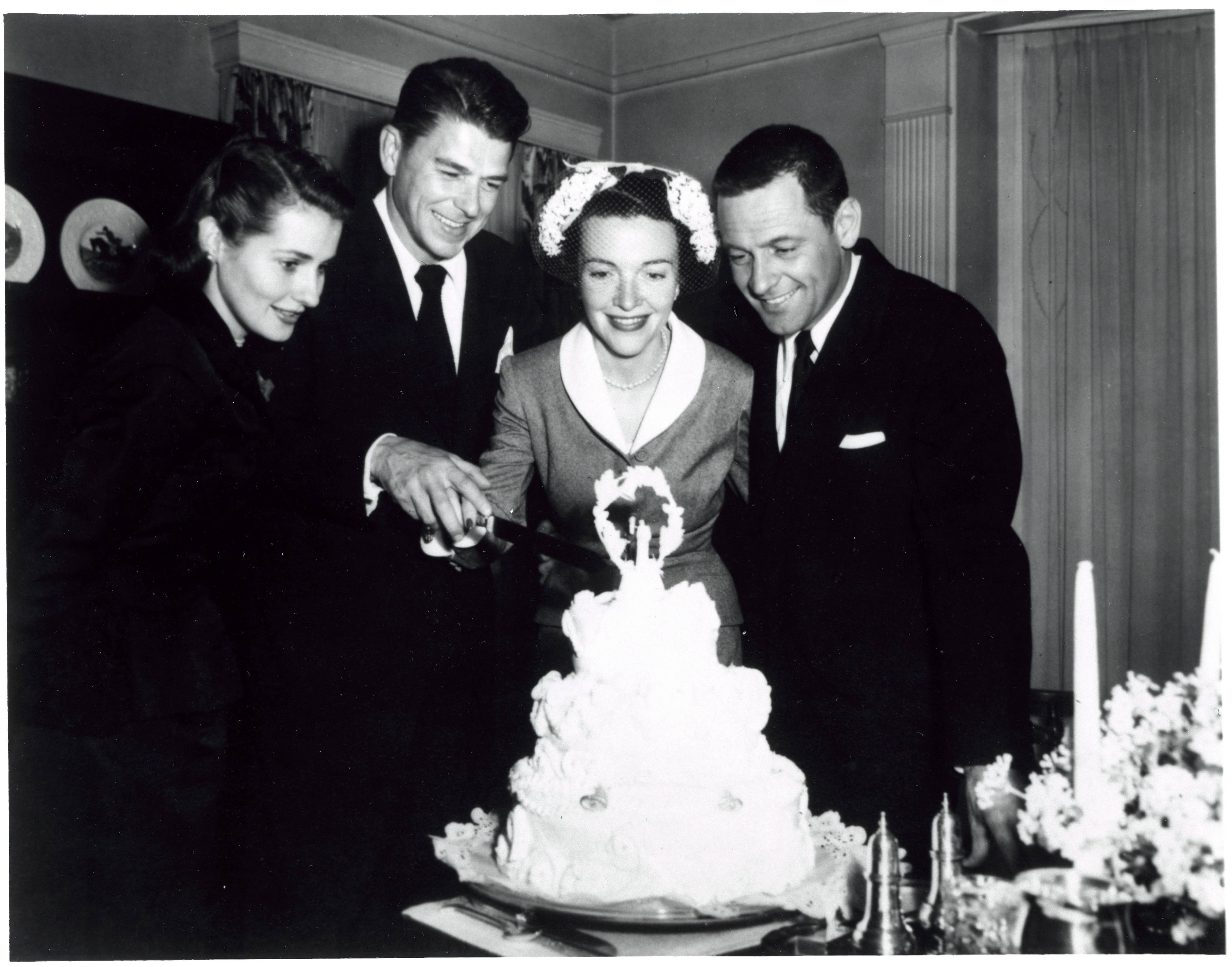 Ronald Reagan, Nancy Reagan, William Holden and Ardis Holden cutting cake after the Reagan’s wedding at the Holden’s house in Toluca Lake, California