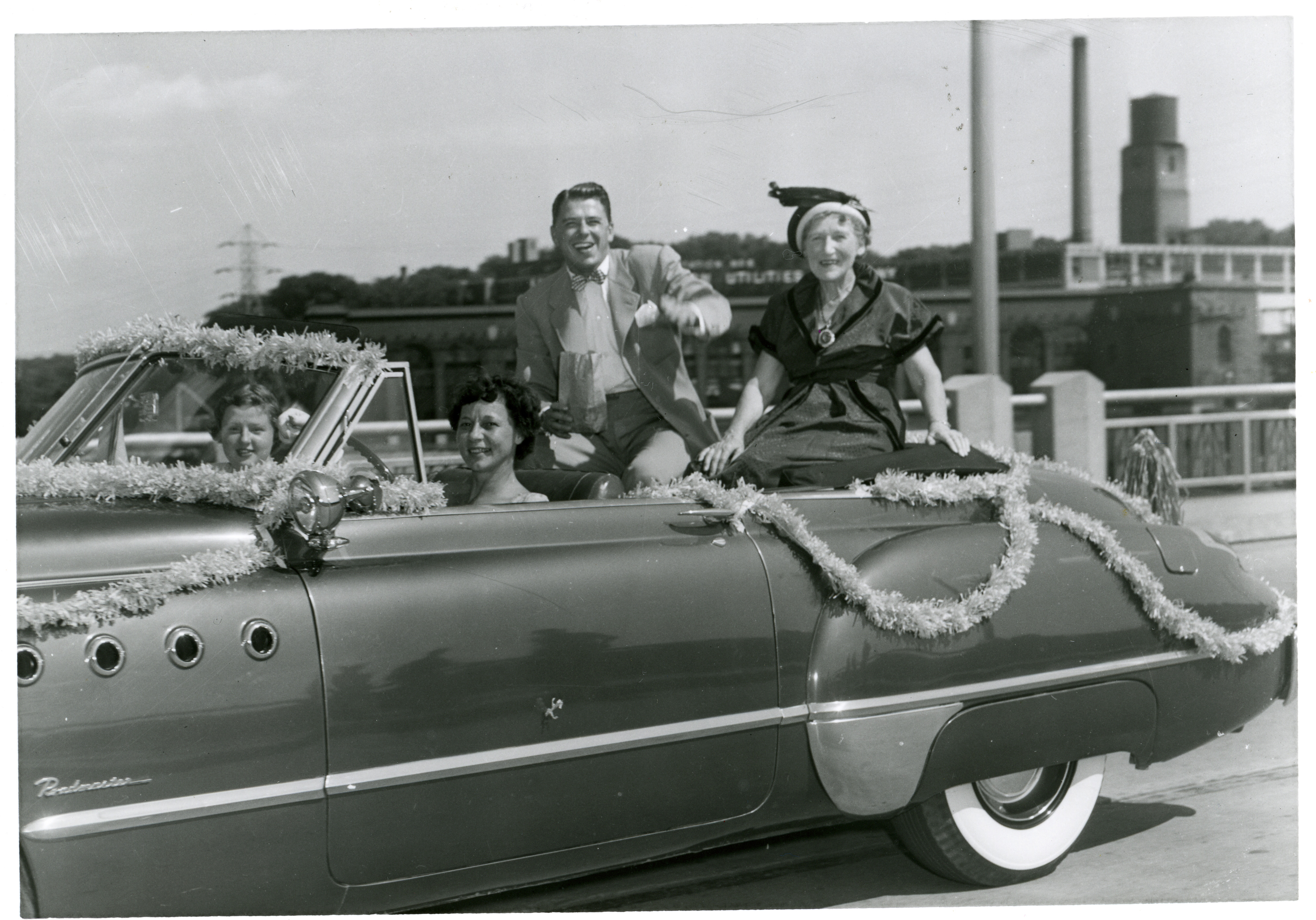 Ronald Reagan, Nelle Reagan riding in convertible car in parade in Dixon, Illinois